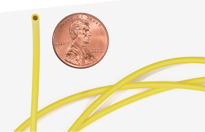 Image showing what a catheter used during a right heart cath looks like, with a penny shown for scale.